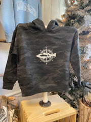Black camo sweatshirt with a white logo on a wooden stand against a snowy outdoor background.